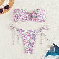 Bikini bandeau rembourré imprimé fleuri posé à plat sur une moquette blanche, chapeau de paille et lunettes
