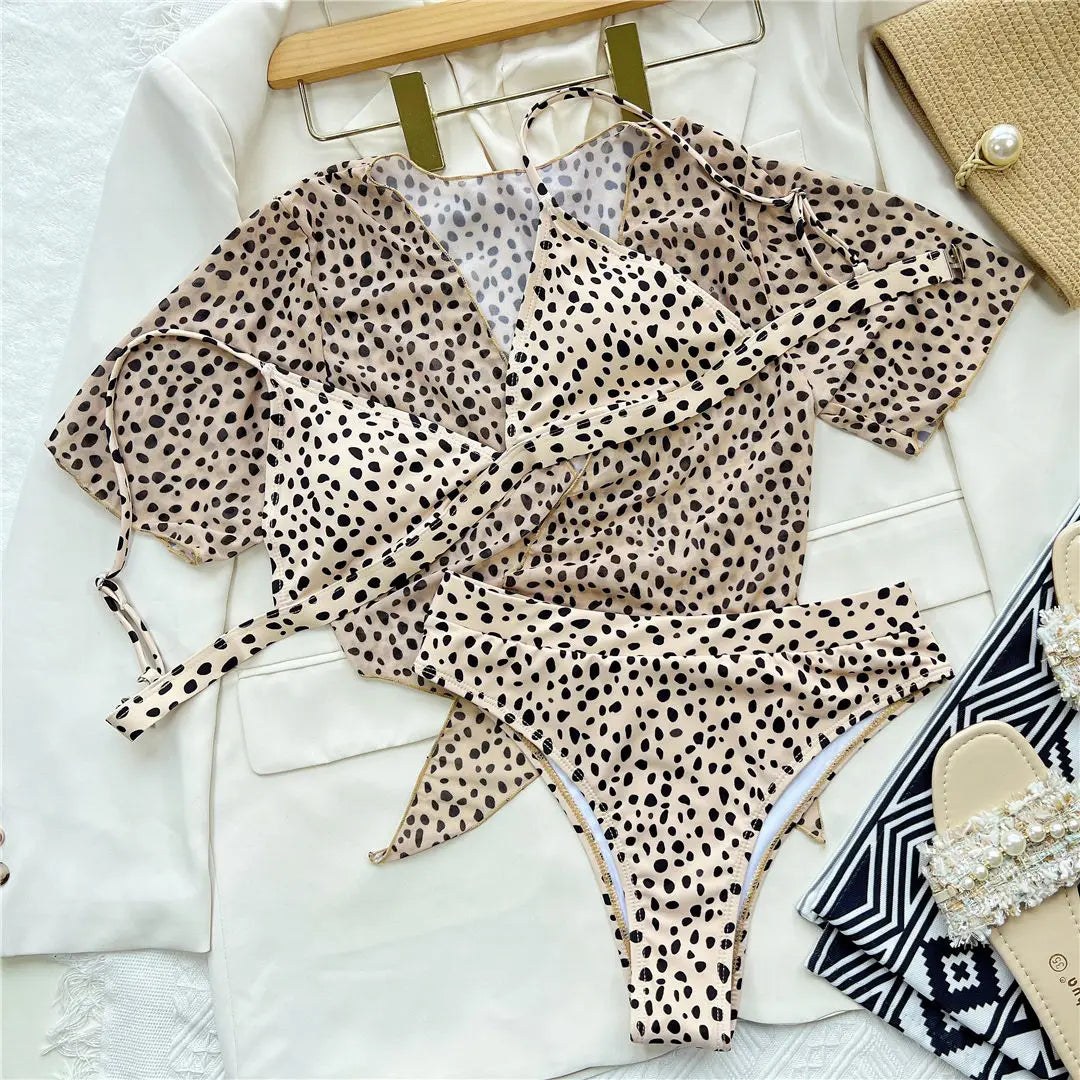 Maillot trois pièces taille haute imprimé léopard posé à plat sur une veste blanche, haut en voile à nouer