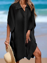 Chemise de plage longue à manches courtes en maille noir portée de face, boutons devant et fente latérale sur le sable