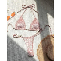 Bikini string triangle sans armatures imprimé léopard rose posé à plat sur fond gris, ombre de soleil et bretelles étirées
