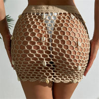 Jupe de plage beige clair en crochet ajouré, vue de dos avec les mains sur les hanches et coquillages en quinconce