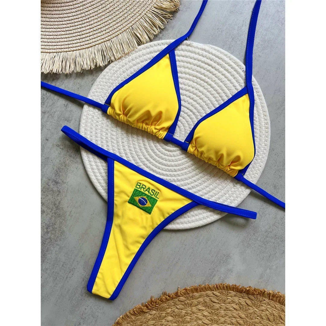 Bikini brésilien string sans armatures taille basse jaune à liseré bleu posé à plat sur un plateau en osier
