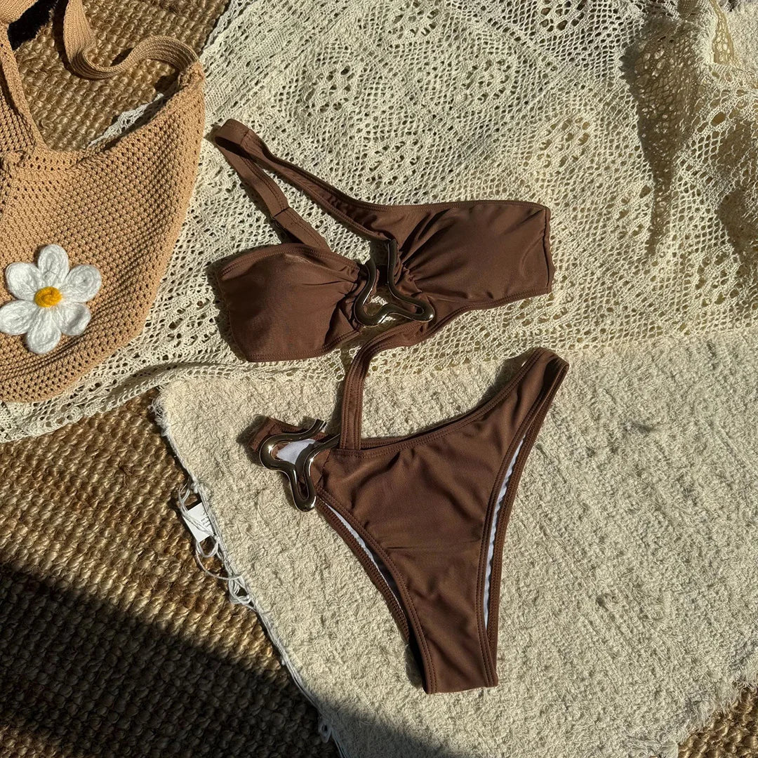 Maillot de bain marron café posé à plat sur un tapis crocheté, haut bandeau et bas séparés avec anneau argenté au centre