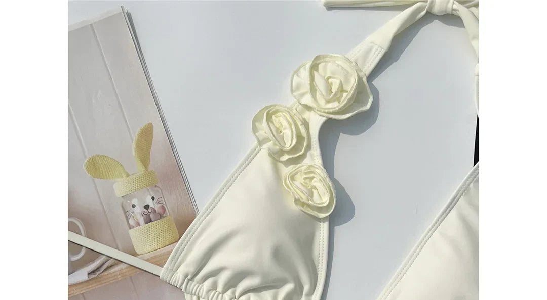 Gros plan sur le haut du maillot une pièce décolleté plongeant fleurs 3D blanc cassé