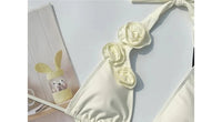 Gros plan sur le haut du maillot une pièce décolleté plongeant fleurs 3D blanc cassé
