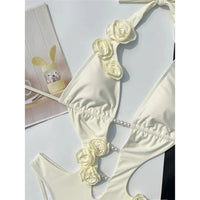 Gros plan sur les fleurs 3D crème du maillot une pièce décolleté V, perles au centre et bretelles nouées