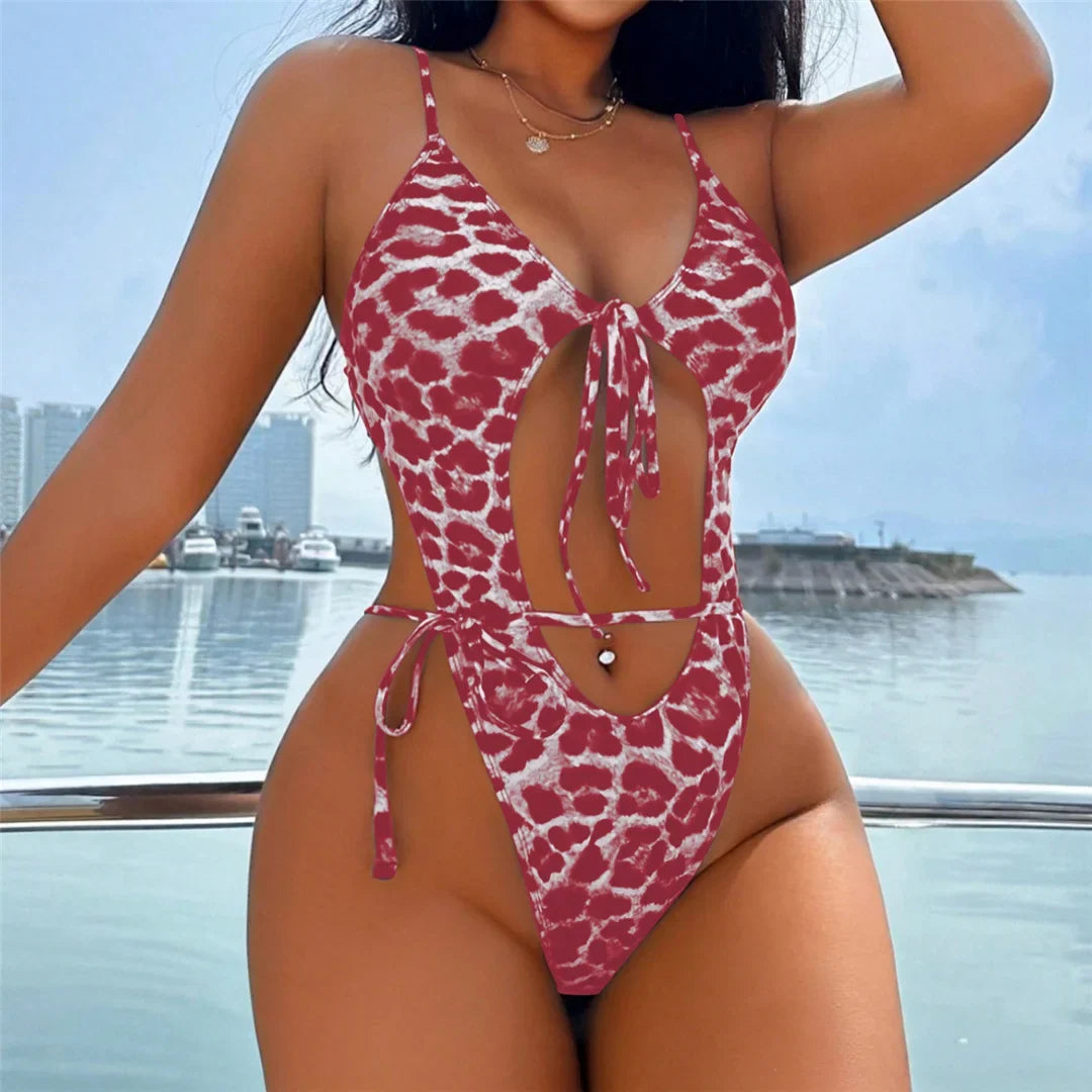 Maillot de bain une pièce échancré à nœud imprimé léopard rouge porté de face, bras le long du corps, mer en arrière-plan
