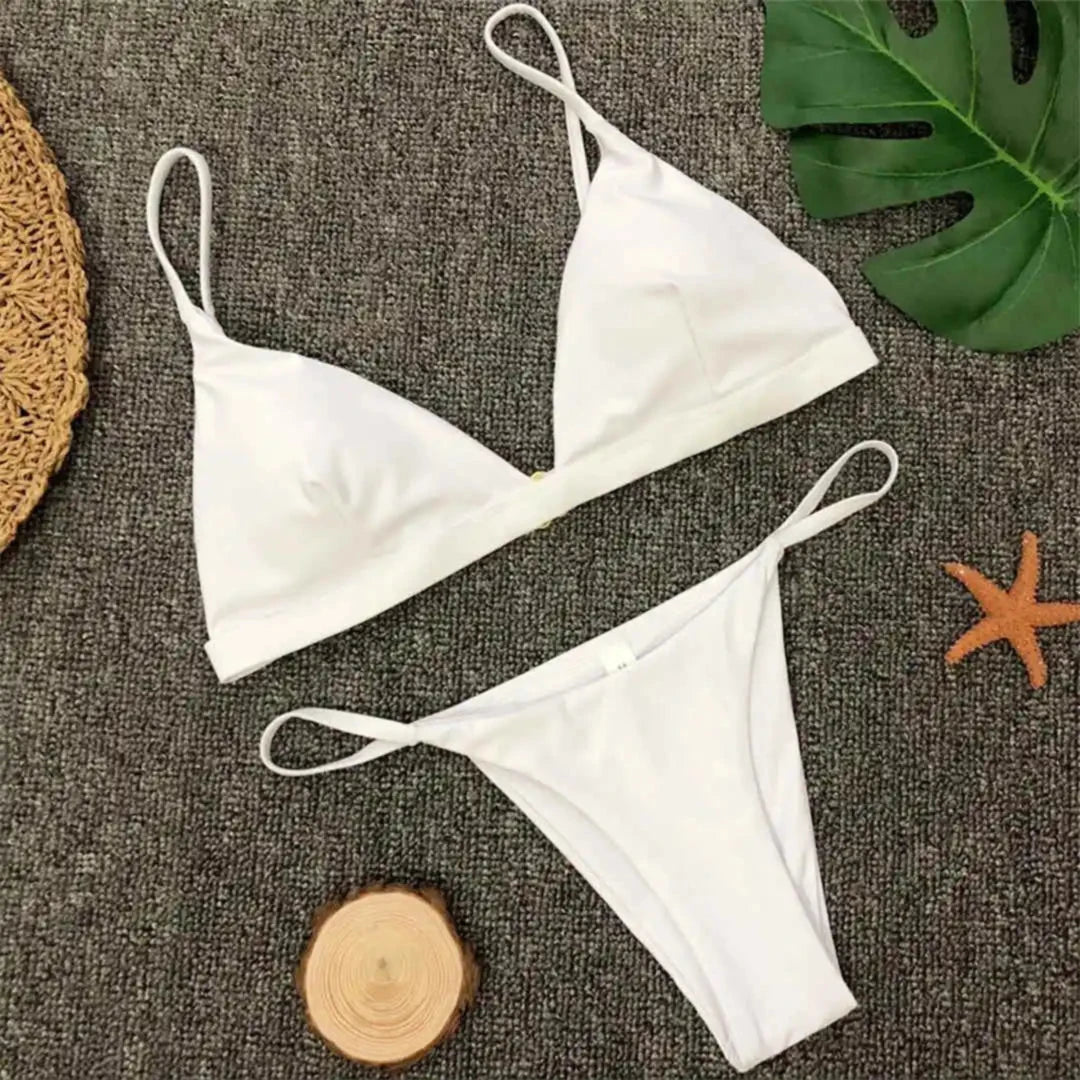 Bikini brésilien rembourré à taille basse blanc posé à plat sur tapis gris, cordelettes fines et étoile de mer orange