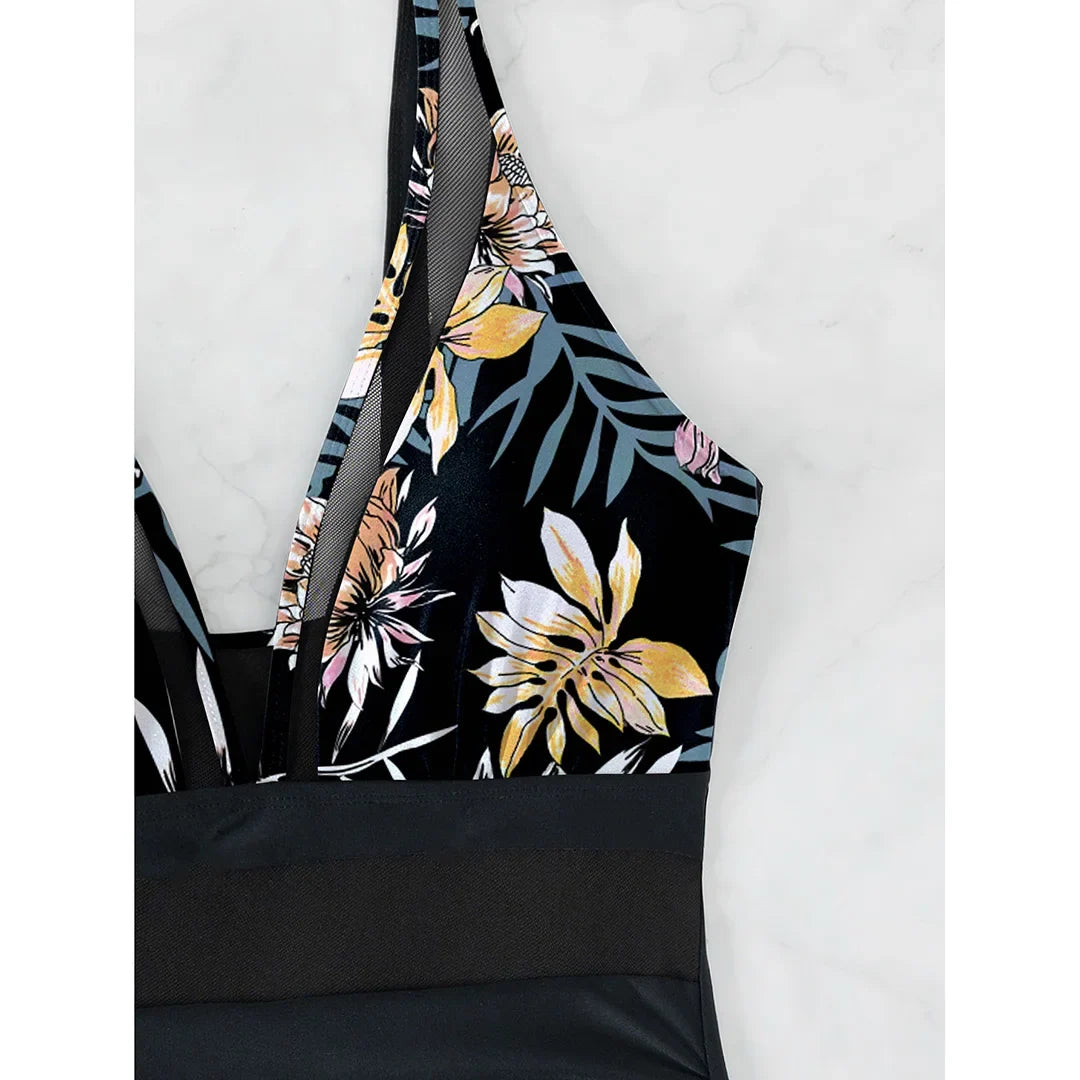 Gros plan sur le haut imprimé feuilles du maillot, fleurs jaunes et feuilles vert gris sur fond noir et mesh transparent