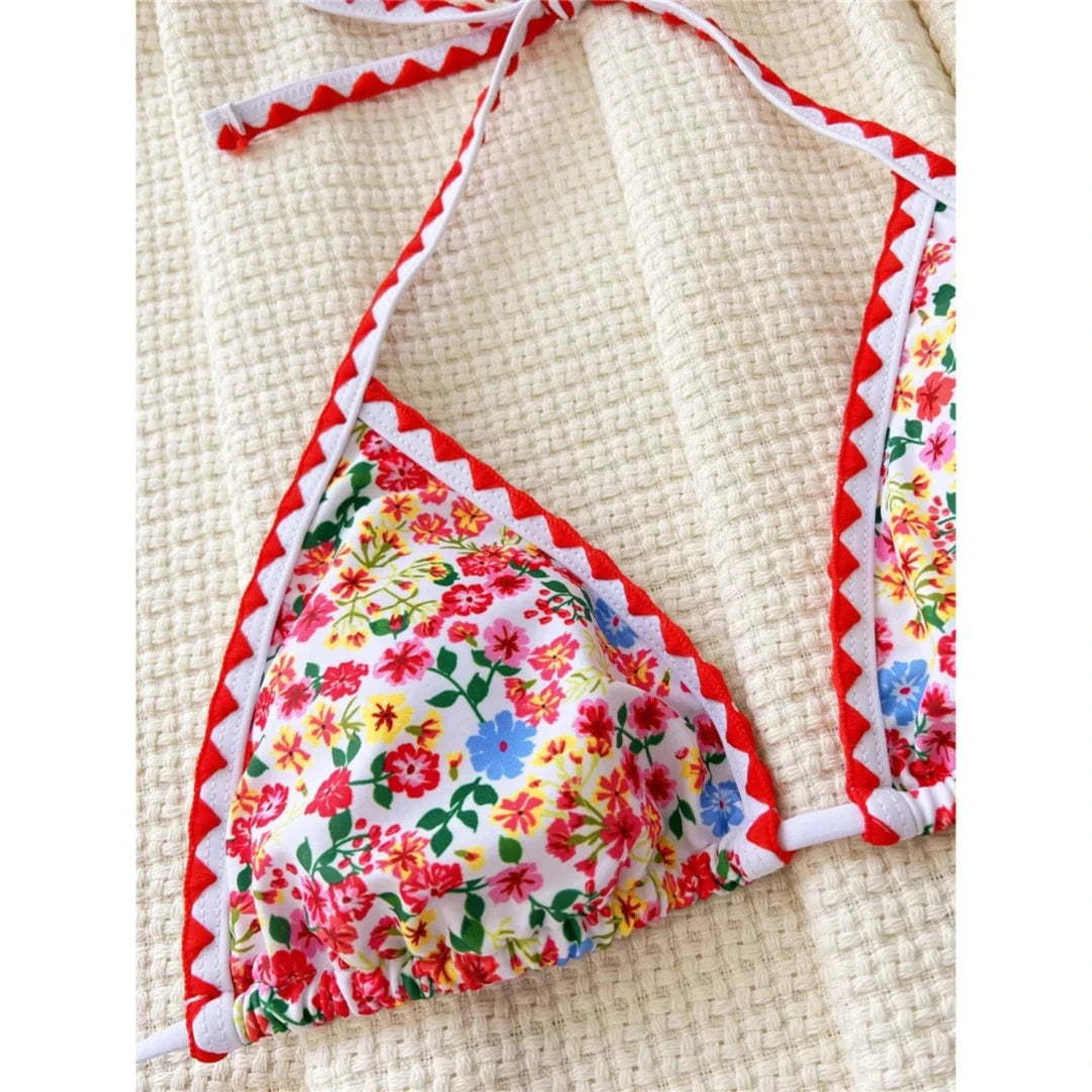 Gros plan sur le triangle à petites fleurs d'un bikini, bordure rouge et blanche en zigzag et lien de nuque