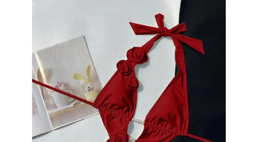 Gros plan sur le haut du maillot une pièce décolleté plongeant fleurs 3D rouge