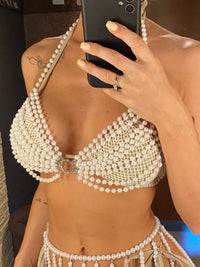 Top de plage à perles ajouré tour de cou blanc porté de face par une femme, rangs de perles descendant jusqu'à la taille