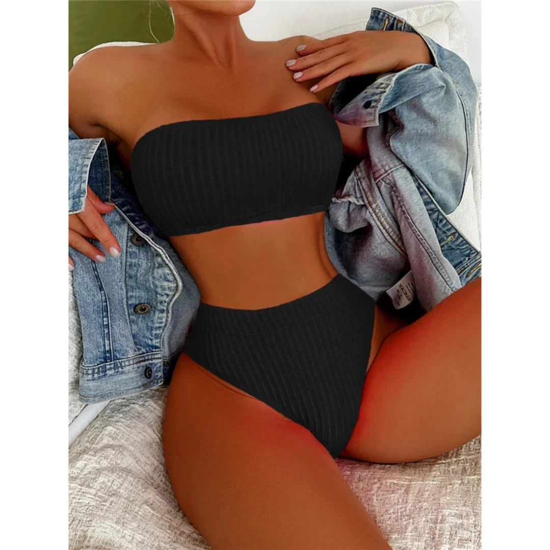 Bikini bandeau taille haute texturé noir porté de face par une femme allongée, veste en jean posée sur les épaules