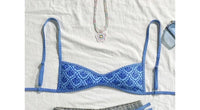 Gros plan sur le haut du bikini à bretelles fines échancré imprimé géométrique bleu