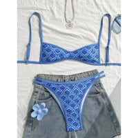 Bikini triangle bleu imprimé fleuri à plat sur un short en jean, bretelles étirées et fleur bleue posée sur la poche