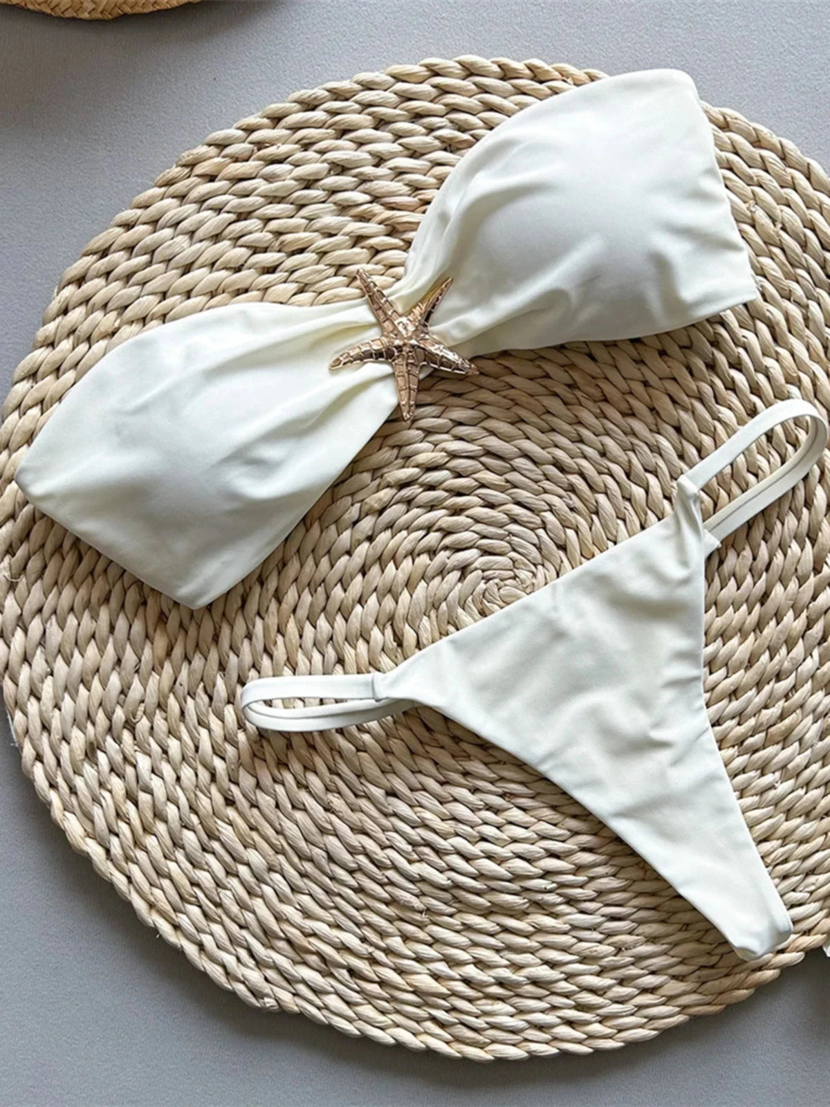 Bikini bandeau string échancré à étoile métallique beige à plat, étoile dorée sur le haut et bretelles fines du slip