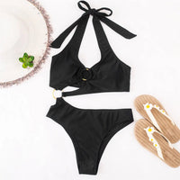 Monokini une pièce asymétrique tour de cou noir posé à plat avec tongs et chapeau, anneau doré et découpe latérale