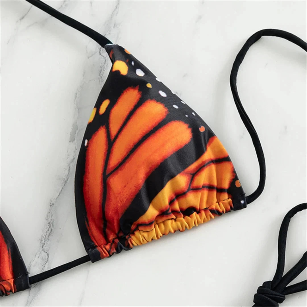 Maillot de bain deux pièces tour de cou imprimé rouge, gros plan sur le haut triangle aux ailes orange et noires bordé de liens