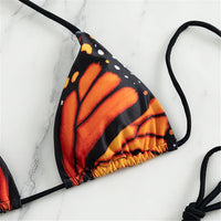 Maillot de bain deux pièces tour de cou imprimé rouge, gros plan sur le haut triangle aux ailes orange et noires bordé de liens