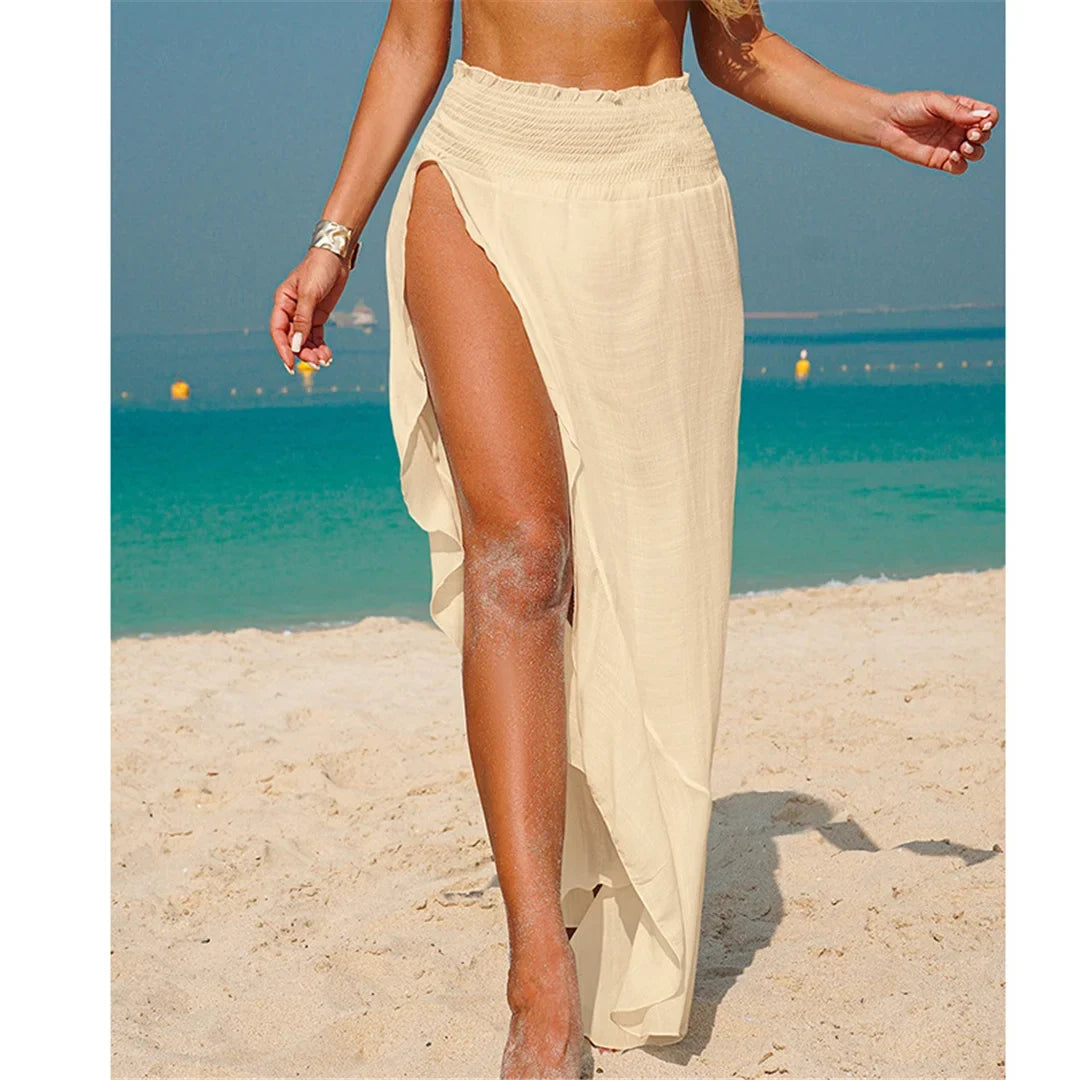 Jupe de plage beige longue à fente haute, taille élastiquée et bas à volants, portée de face sur le sable