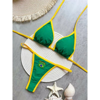 Bikini brésilien string sans armatures taille basse vert posé à plat sur un plateau en osier avec coquillages