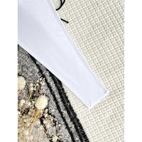 Gros plan sur le bord latéral échancré d'un maillot une pièce blanc posé sur un tissu gris et noir