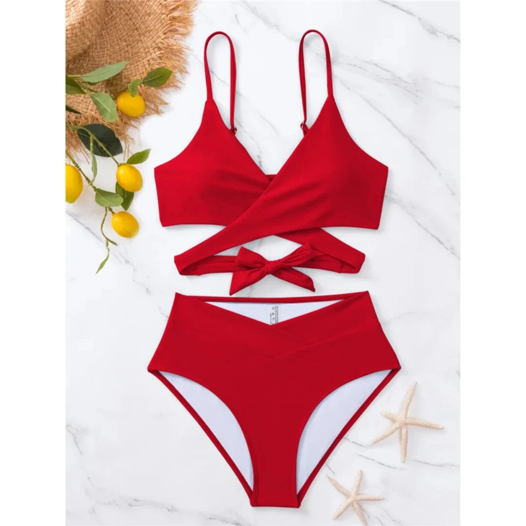 Bikini taille haute décolleté en V rouge posé à plat sur marbre, haut à lanières croisées autour du buste et culotte taille haute, citrons en décor