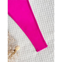 Gros plan sur le bord latéral échancré d'un maillot une pièce rose fuchsia posé sur un tissu blanc