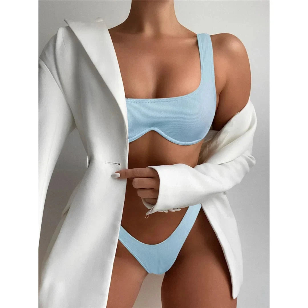 Bikini à armatures brésilien détail en V bleu clair porté de face sous un blazer blanc, bonnets à armatures