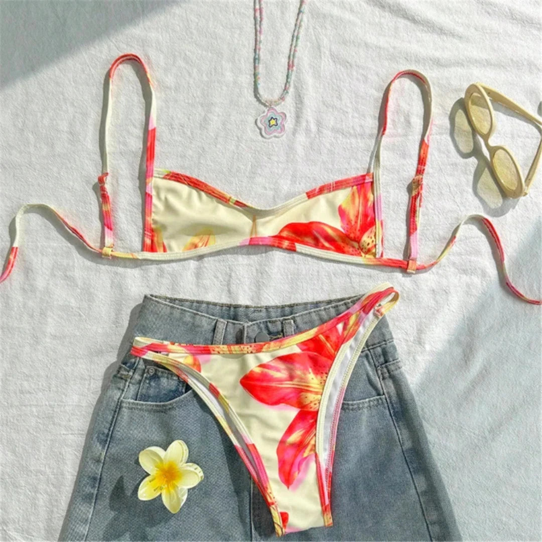 Bikini triangle échancré imprimé fleuri jaune crème posé à plat sur un short en jean, fleurs rouges et bretelles fines