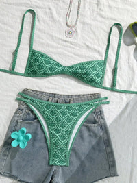 Bikini triangle échancré vert imprimé fleuri à plat sur un short en jean avec une fleur verte posée sur la poche