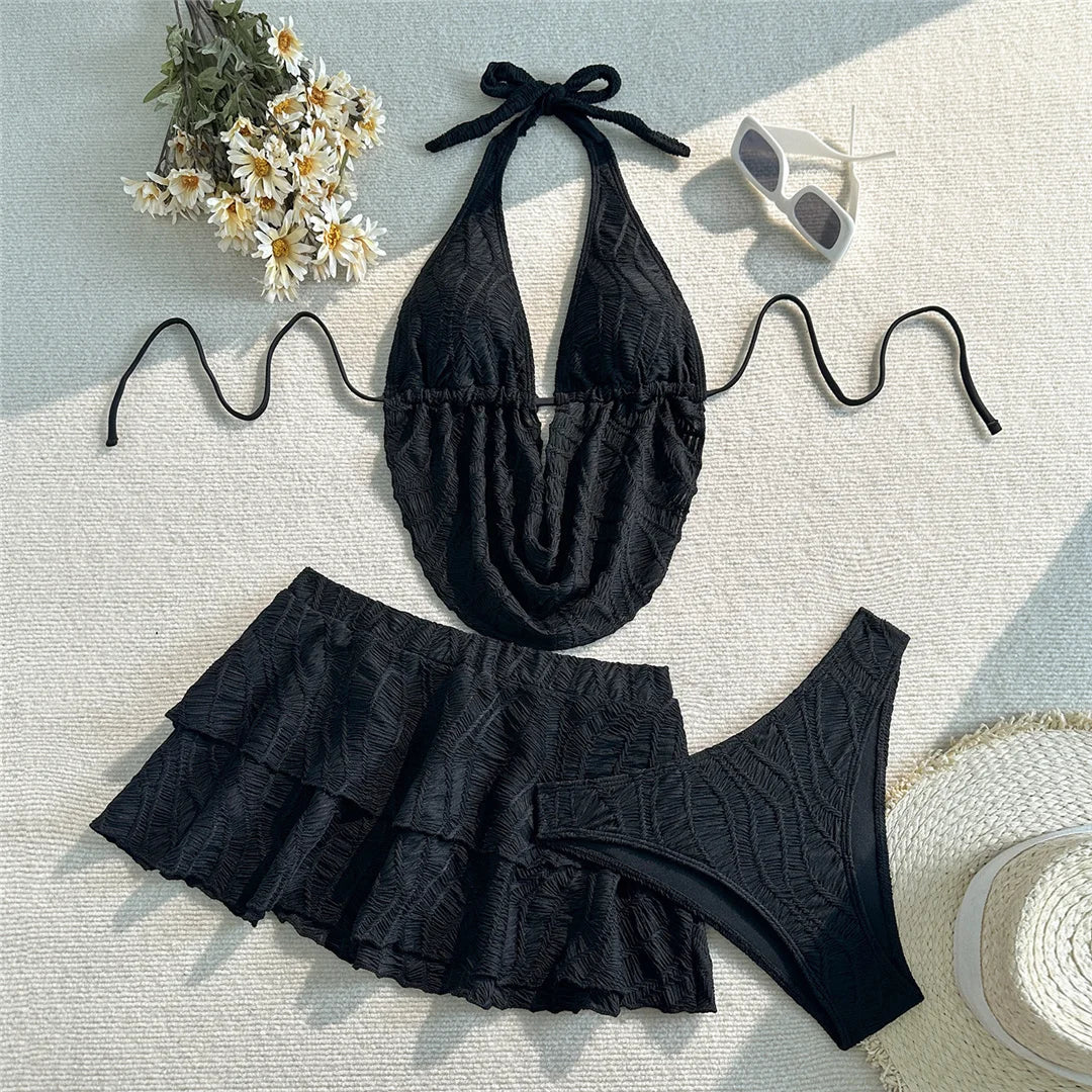 Maillot de bain trois pièces tankini avec jupe texturé noir posé à plat sur fond blanc avec marguerites et lunettes