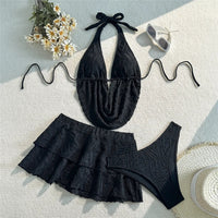 Maillot de bain trois pièces tankini avec jupe texturé noir posé à plat sur fond blanc avec marguerites et lunettes