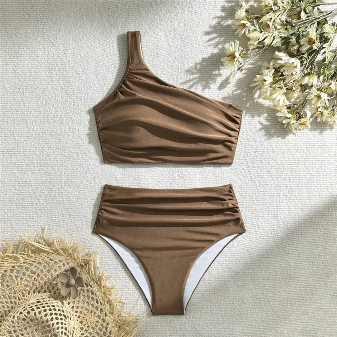 Bikini une épaule taille haute marron froncé posé à plat sur fond clair, haut asymétrique et bas drapé