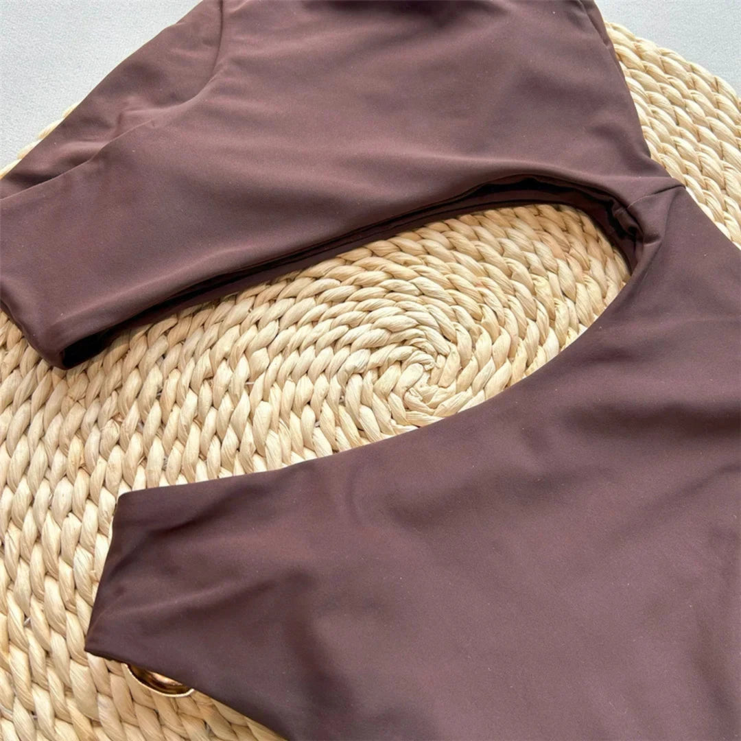 Gros plan sur l'anneau métal doré et la découpe du maillot de bain une pièce marron posé sur de l'osier