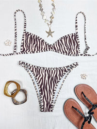 Bikini triangle sans coques taille basse imprimé zèbre marron posé à plat avec colliers, sandales et bracelets autour