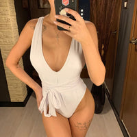 Maillot de bain une pièce plongeant à lien blanc porté de face, décolleté profond et ceinture nouée à la taille