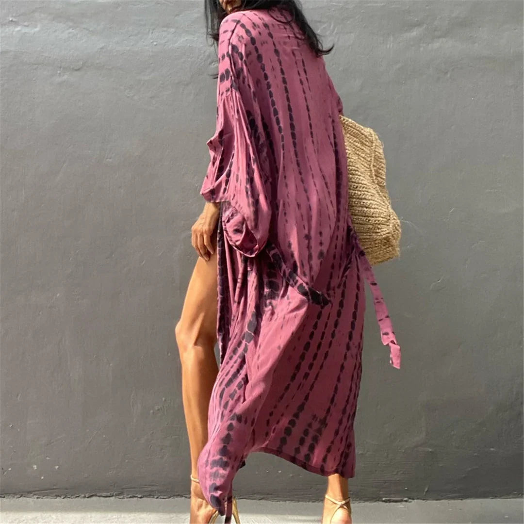 Tunique de plage imprimée manches longues à ceinture rose fuchsia portée de côté, sac en osier sur l'épaule