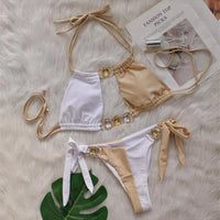 Bikini strass blanc et beige posé à plat sur une fourrure blanche, haut beige et blanc avec anneaux dorés ornés de pierres jaunes
