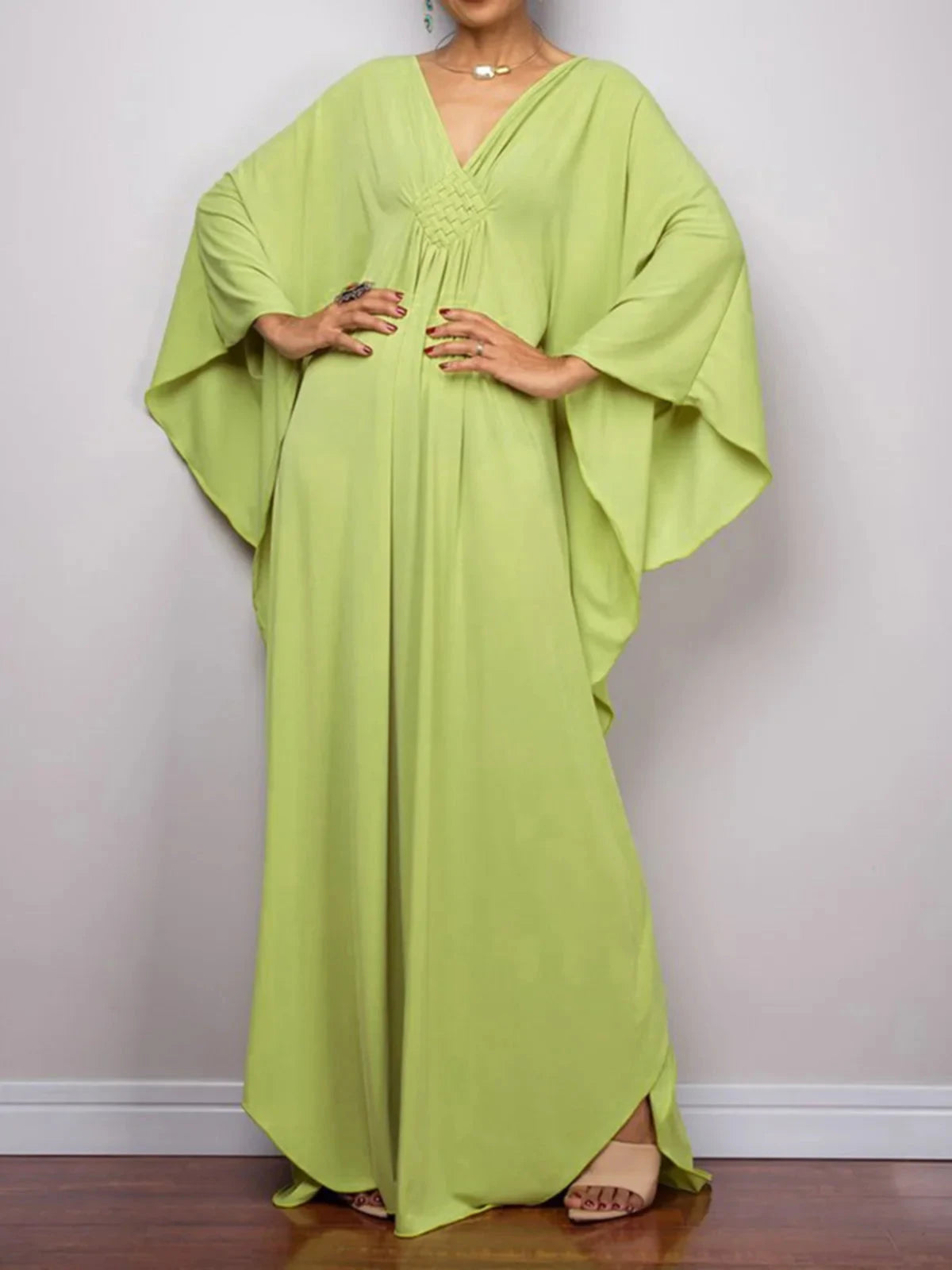 Robe de plage longue kaftan manches chauve-souris vert anis portée de face en plan large, mains sur les hanches et ourlet fendu