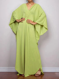 Robe de plage longue kaftan manches chauve-souris vert anis portée de face en plan large, mains sur les hanches et ourlet fendu