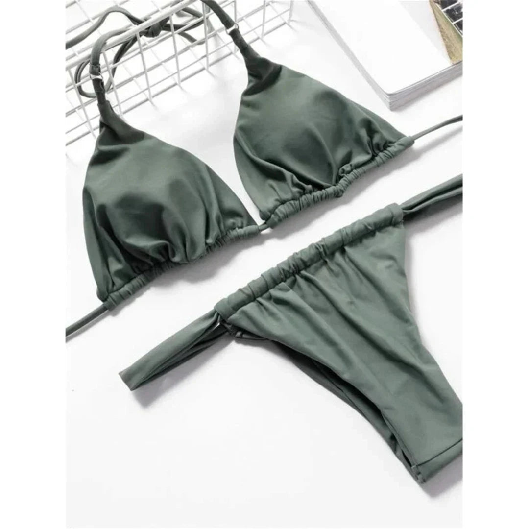 Bikini string triangle froncé vert militaire posé à plat sur une chaise en métal, bas taille basse à bandes larges