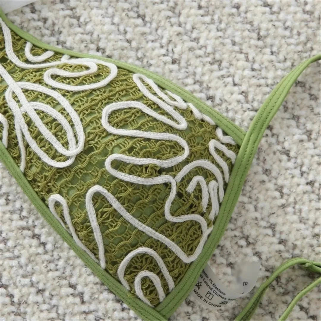 Gros plan sur le tissu vert brodé de motifs blancs d'un bikini, bordure verte et étiquette visible sur le bonnet