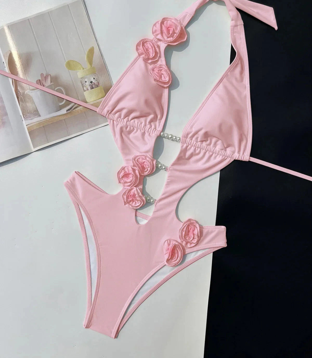 Maillot une pièce rose poudré à décolleté plongeant et fleurs 3D, vue à plat avec bretelles nouées au cou