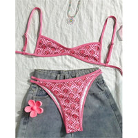 Bikini rose imprimé fleuri posé à plat sur un short en jean, avec une fleur rose et un collier posés à côté