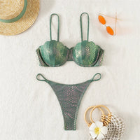 Bikini balconnet string festonné effet serpent vert posé à plat sur tapis blanc, chapeau de paille et fleur en décor
