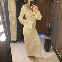 Tunique de plage crochet beige manches longues portée en pied devant un miroir éclairé par des spots, fleur au décolleté