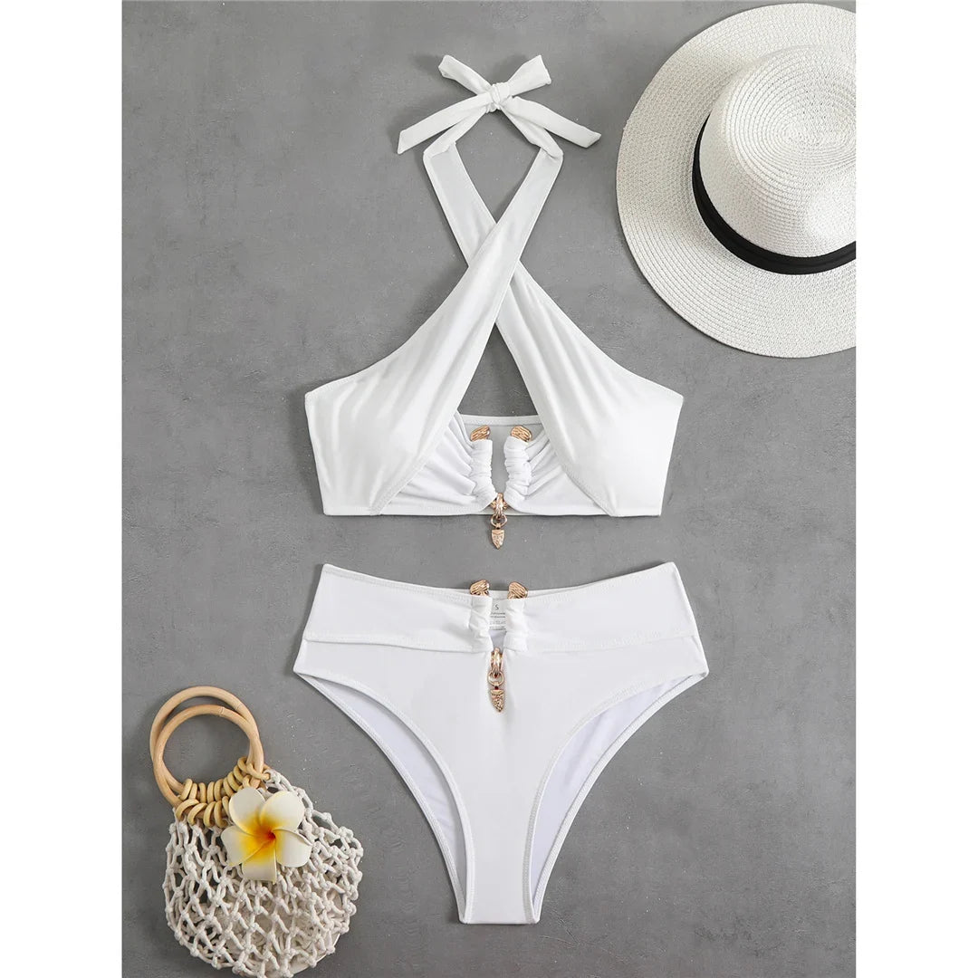 Bikini taille haute tour de cou à découpes blanc posé à plat sur fond gris, chapeau et sac en filet à côté