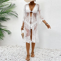 Cardigan de plage brodé en mousseline demi-manches blanc porté de face par une femme debout, sandales plates