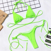 Bikini string croisé sans armatures taille basse vert fluo porté de face, lacets croisés sur le ventre et slip à nouer